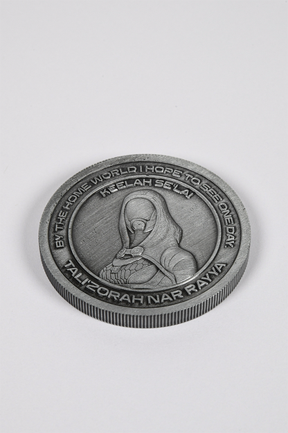 Image shows Mass Effect Coin Album's Tali'Zorah coin laid flat facing front. Coin features Tali'Zorah's logo in the middle surrounded by one of her famous quotes. 