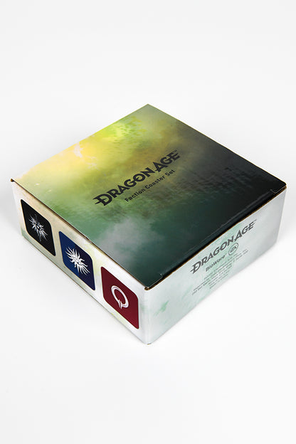 Image shows a closed box facing a right angle that holds all 6 coasters with the Dragon Age name on top. The left side shows the Inquistion, Seekers of Truth, and Circle of Magi symbols. 
