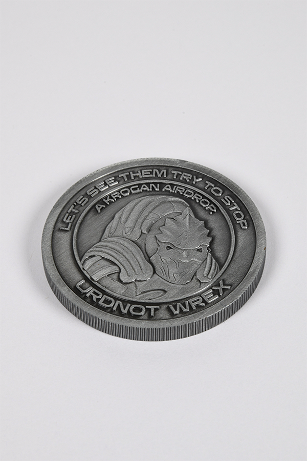 Image shows Mass Effect Coin Album's Urdnot Coin laid flat facing front. Coin features Urdnot's logo in the middle surrounded by one of his famous quotes. A famed krogan mercenary and bounty hunter, Urdnot Wrex is also one of the last Krogan Battlemasters: rare individuals who combine powerful biotic abilities with the devastating firepower of advanced weaponry. 