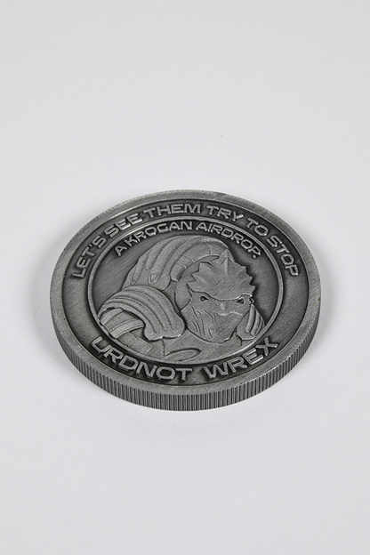 Image shows Mass Effect Coin Album's Urdnot Coin laid flat facing front. Coin features Urdnot's logo in the middle surrounded by one of his famous quotes. A famed krogan mercenary and bounty hunter, Urdnot Wrex is also one of the last Krogan Battlemasters: rare individuals who combine powerful biotic abilities with the devastating firepower of advanced weaponry. 