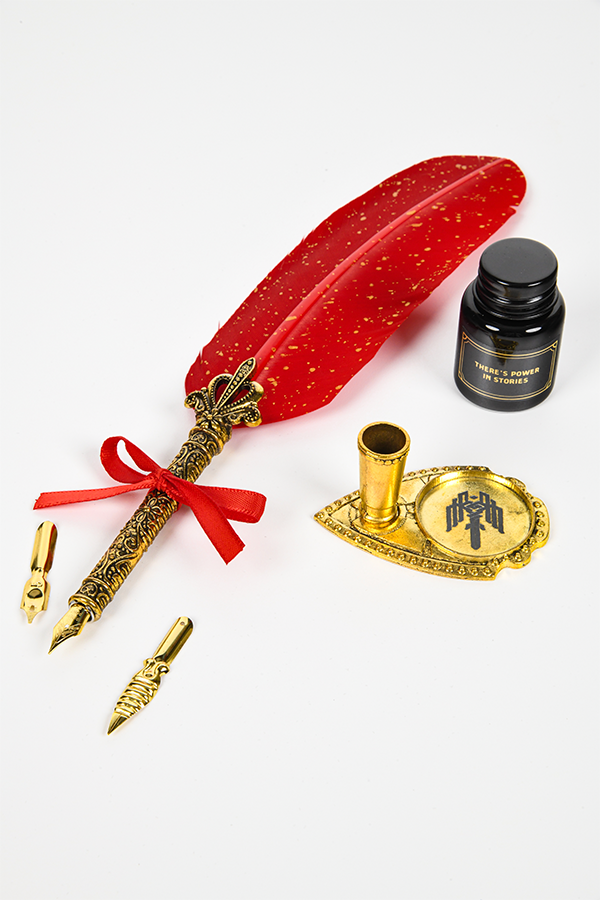 Image shows Dragon Age Varric Writing Box Essential Bundle's pen, tips, ink holder and pen holder laid on a surface all facing at an angle. The ink and pen holder have laser etched logos.
