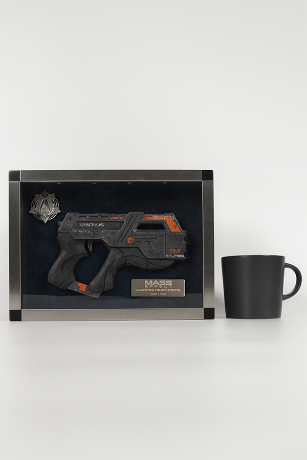 Image shows Mass Effect Carnifex Replica Shadowbox facing front beside a black mug for scale. The gun has a dial on the side with "Auto" written next to it, suggesting that the weapon can be fired full auto. This can be seen when modding in Mass Effect 3.