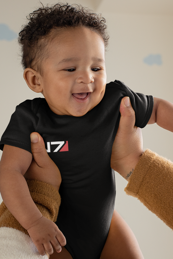 Image shows male baby model being held up while wearing the N7 I Have To Go Baby Onesie. Product is black in color made with 100% combed ringspun cotton 1x1 baby rib