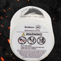 Image shows Dragon Age Fen Harel Scented Candle laid flat with its bottom facing front showing the Bioware and EA logos with the warning notices written. Product is made with coconut soy wax and 100% cotton wick.