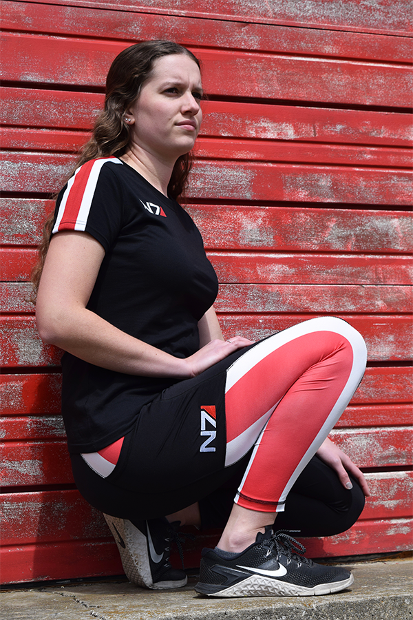 Image shows Mass Effect N7 Ankle Legging worn by female model squatting. Product features a squat-proof material and 4-way stretch.