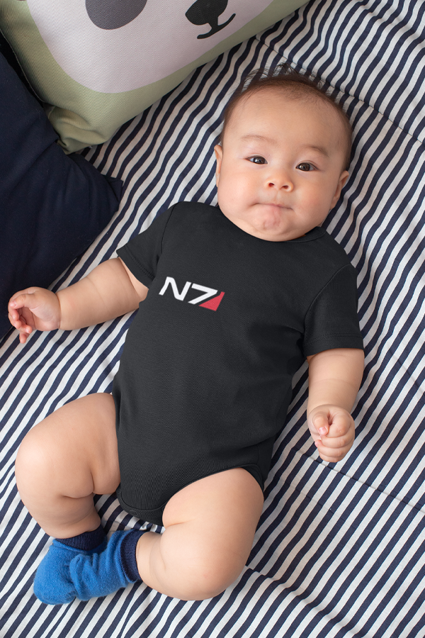 Image shows N7 I Have To Go Baby Onesie worn by male baby while lying flat on a bed. Product has a CPSIA compliant tracking label in its side seam.