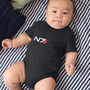 Image shows N7 I Have To Go Baby Onesie worn by male baby while lying flat on a bed. Product has a CPSIA compliant tracking label in its side seam.