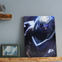 Image shows Mass Effect Archangel Small Canvas Print facing front standing on a wall shelf. Product features Garrus Vakarian and his silvery skin, metal shoulder plate, bionic eye mask and steely blue eyes.