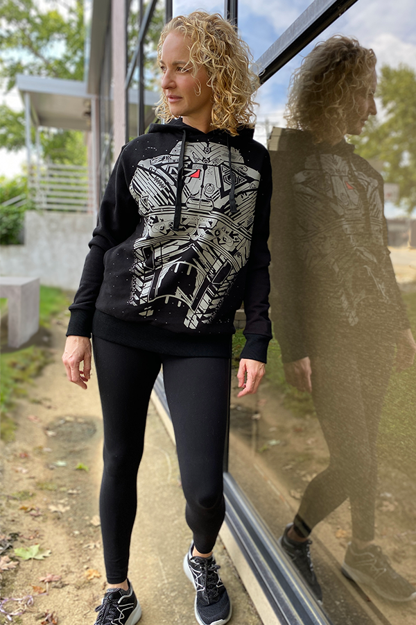 Image shows Mass Effect N7 Armour Hoodie worn by female model facing at an angle. Product has a reflective front print with kangaroo pockets.