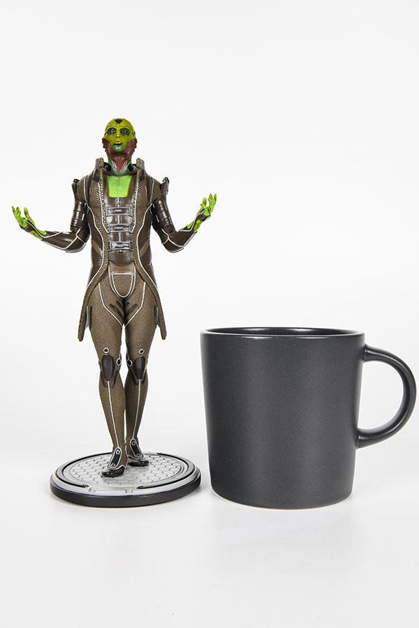 Image shows Thane Krios Statue standing up facing front beside a mug (for scale).
