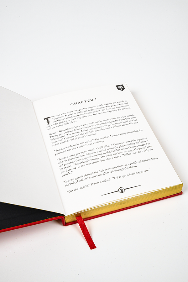 Image shows Dragon Age Varric Writing Box Essential Bundle's Journal opened and laid flat. Product is dedicated to Bianca with the inner page printed with chapter one. Each page features an upper corner and center bottom motif.