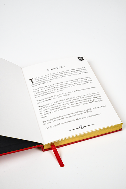 Image shows Dragon Age Varric Writing Box Essential Bundle's Journal opened and laid flat. Product is dedicated to Bianca with the inner page printed with chapter one. Each page features an upper corner and center bottom motif.