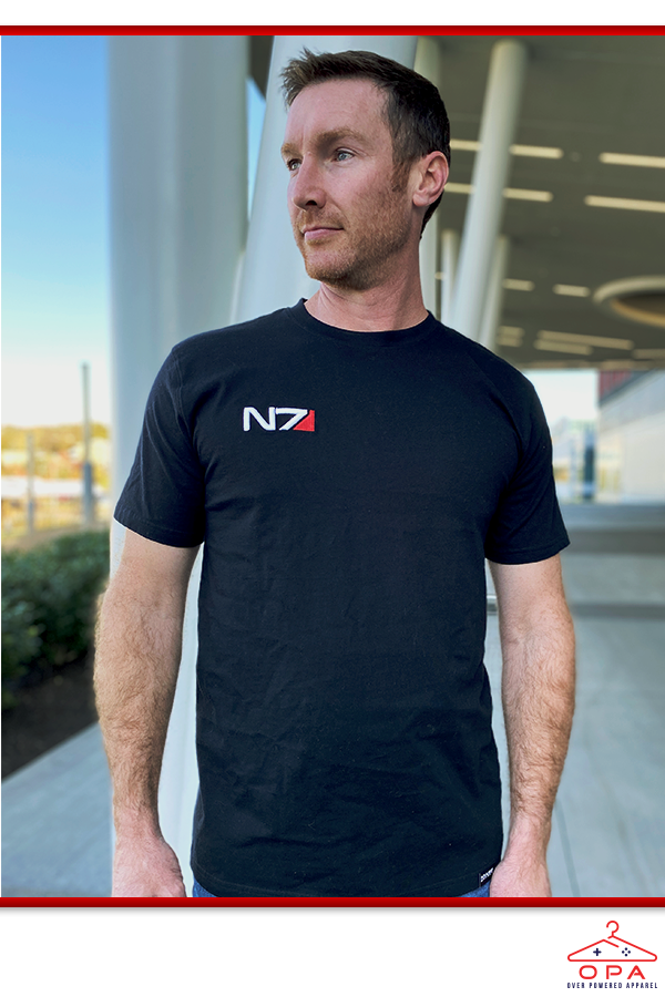 Image shows Mass Effect N7 3D Embroidered OPA T-Shirt worn by a male model facing front at an angle. The N7 emblem is visible on all customizable armor chest pieces wearable by Commander Shepard except for the Kestrel Torso Sheath and the Rosenkov Materials chest piece.
