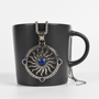 Image shows the Amulet Necklace hanging from the mouth of the mug facing front. The amulet has a 22