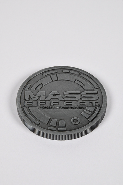 Image shows Mass Effect Coin Album's coin laid flat facing back. The back of the coin features the Mass Effect logo.