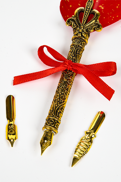 Image shows Dragon Age Varric Writing Box Essential Bundle's Pen and Tips laid flat facing at an angle. The pen is gold with a real feather (sizing varies) and satin ribbon tie.