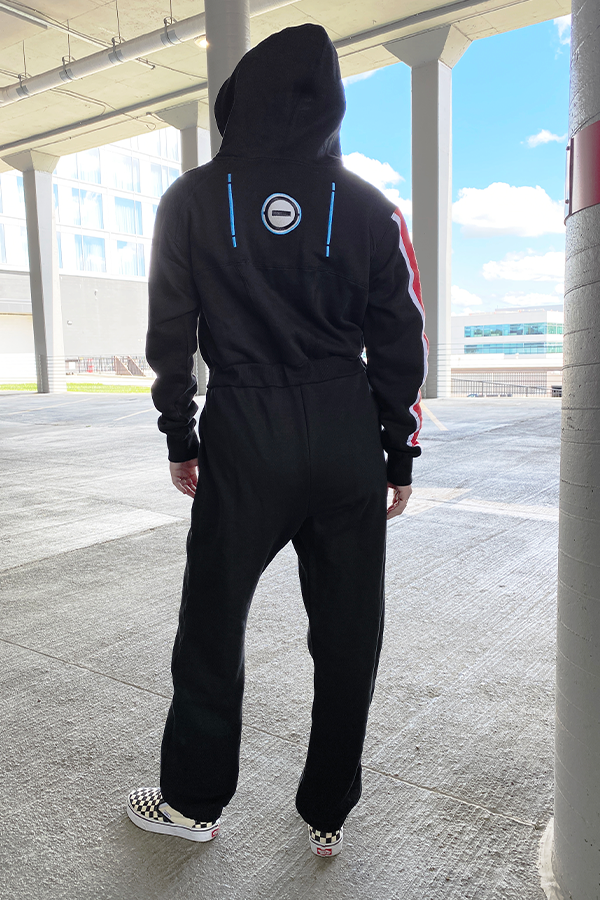 Image shows Mass Effect N7 Adult Onesie Reimagined worn by a model facing back. N7 is a vocational code in the Systems Alliance military. The "N" designates special forces and the "7" refers to the highest level of proficiency. It applies to Alliance personnel who have graduated from the Interplanetary Combatives Training (ICT) program.