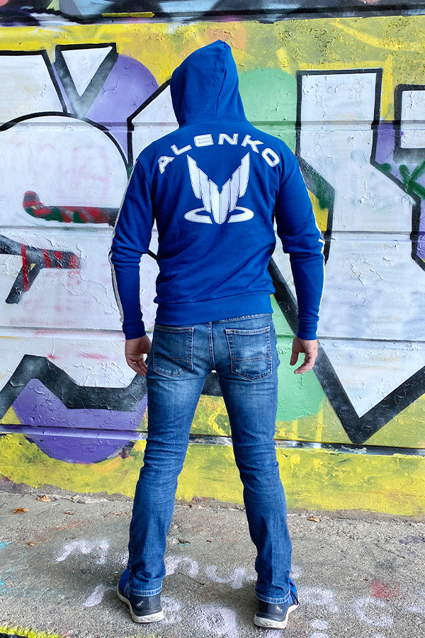 Image shows Mass Effect Team Alenko Hoodie worn by male model facing back. The surname "Alenko" possibly suggests Ukrainian origin; surnames ending in "enko" usually are. "Alenko" would mean "the son of Al". It should be noted, though, that no name "Al" exists in Ukrainian or any slavic language. At the same time, the word "kaidany" ("кайдани") can be translated from Ukrainian as "shackles".