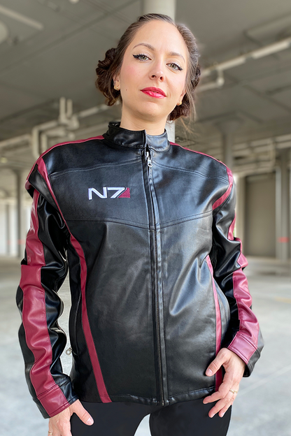 Image shows Mass Effect N7 Jacket Reimagined worn by female model facing front. N7 is a vocational code in the Systems Alliance military. The "N" designates special forces and the "7" refers to the highest level of proficiency. It applies to Alliance personnel who have graduated from the Interplanetary Combatives Training (ICT) program.
