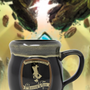 Image shows Dragon Age The Hanged Man Tavern Mug facing front. Product is a black mug and comes with a Hanged Man emblem, a glazed brim, and a C-shaped handle.