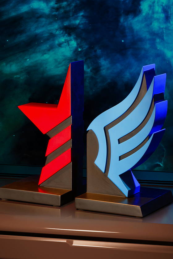 Image shows Mass Effect: Paragon and Renegade Bookends standing up facing at an angle. These themed bookends are designed to represent the symbols of Paragon and Renegade from the Mass Effect games. Made using Polyresin, each piece is 8.5 inches tall and 4.25 inches wide, making them ideal for organizing your book collection. Gift it to a fellow bibliophile or add it to your bookshelf to give it a colorful makeover