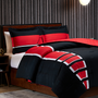 Image shows Mass Effect N7 Bed in a Bag arranged in a bed. Set includes comforter and pillows. The product boasts the red, white, and black colors of the N7. This N7 Bed drapes your wearied body in warmth and comfort.